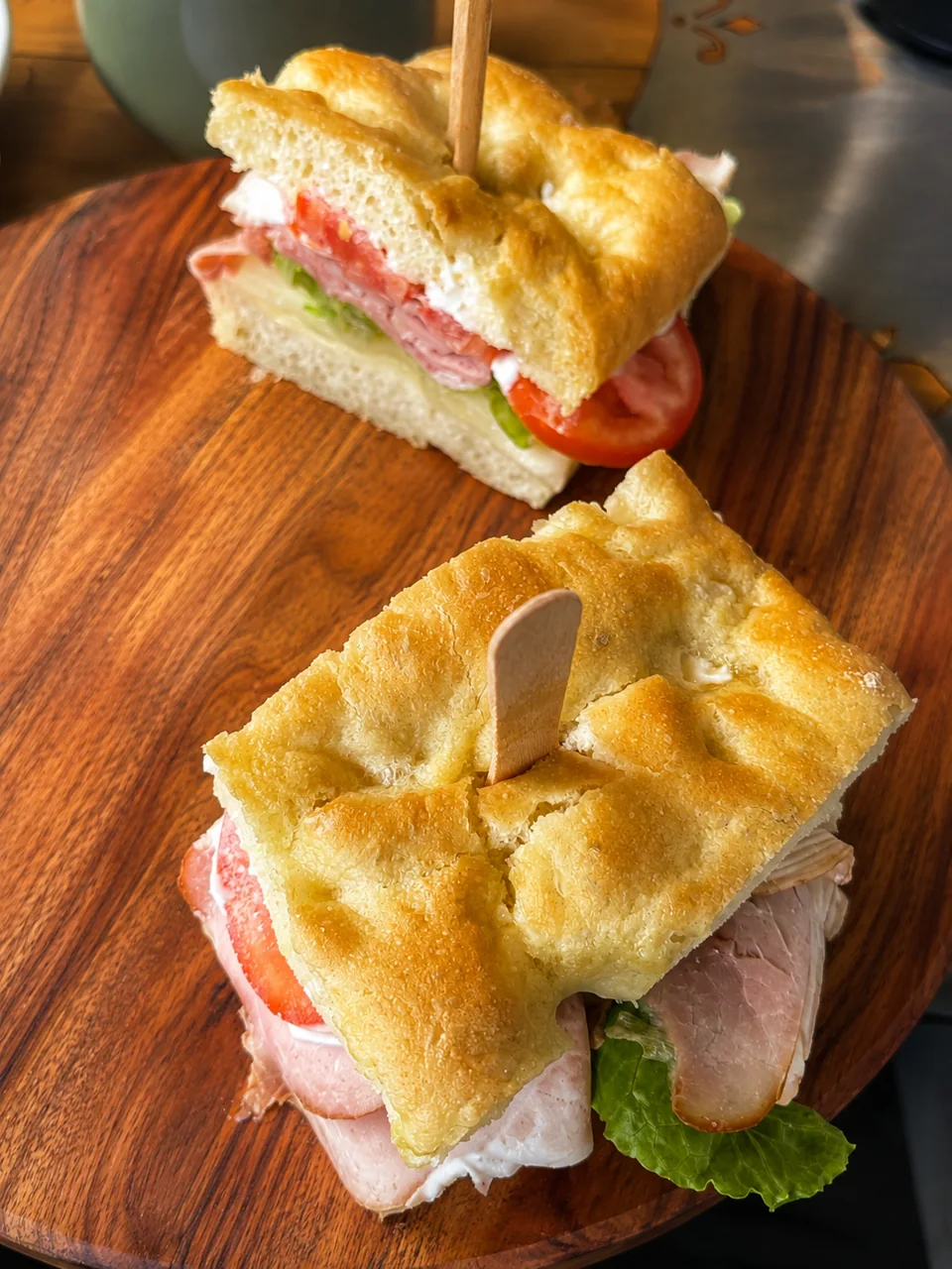 Two sandwiches served on a wooden board at a Pria